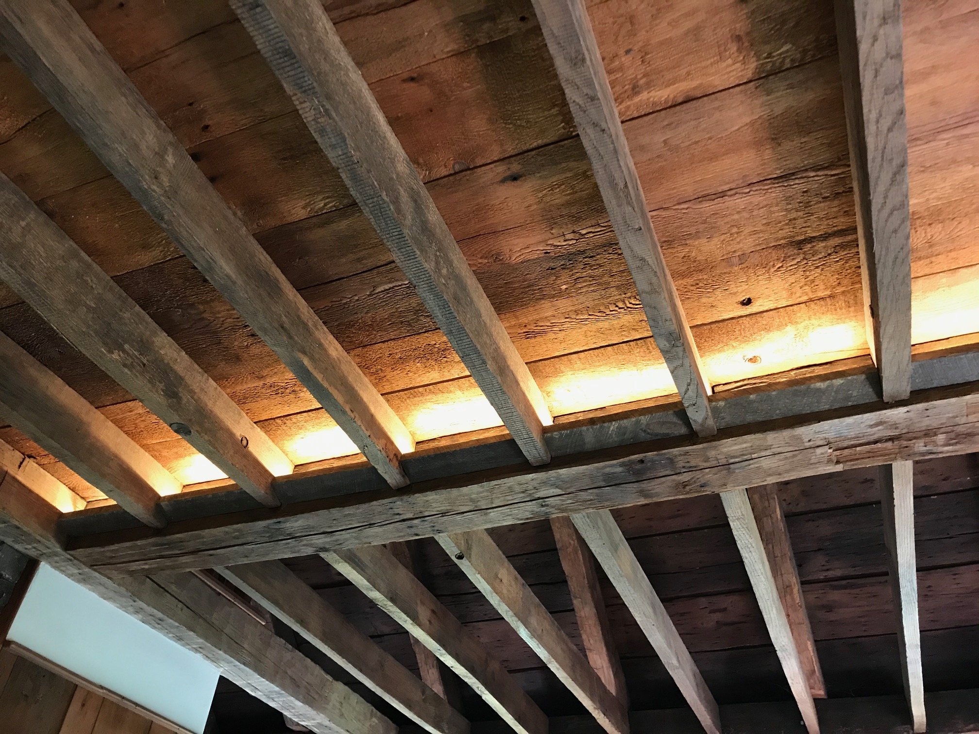 Wooden ceiling frame showing cross beams and plank ceiling with warm lighting.