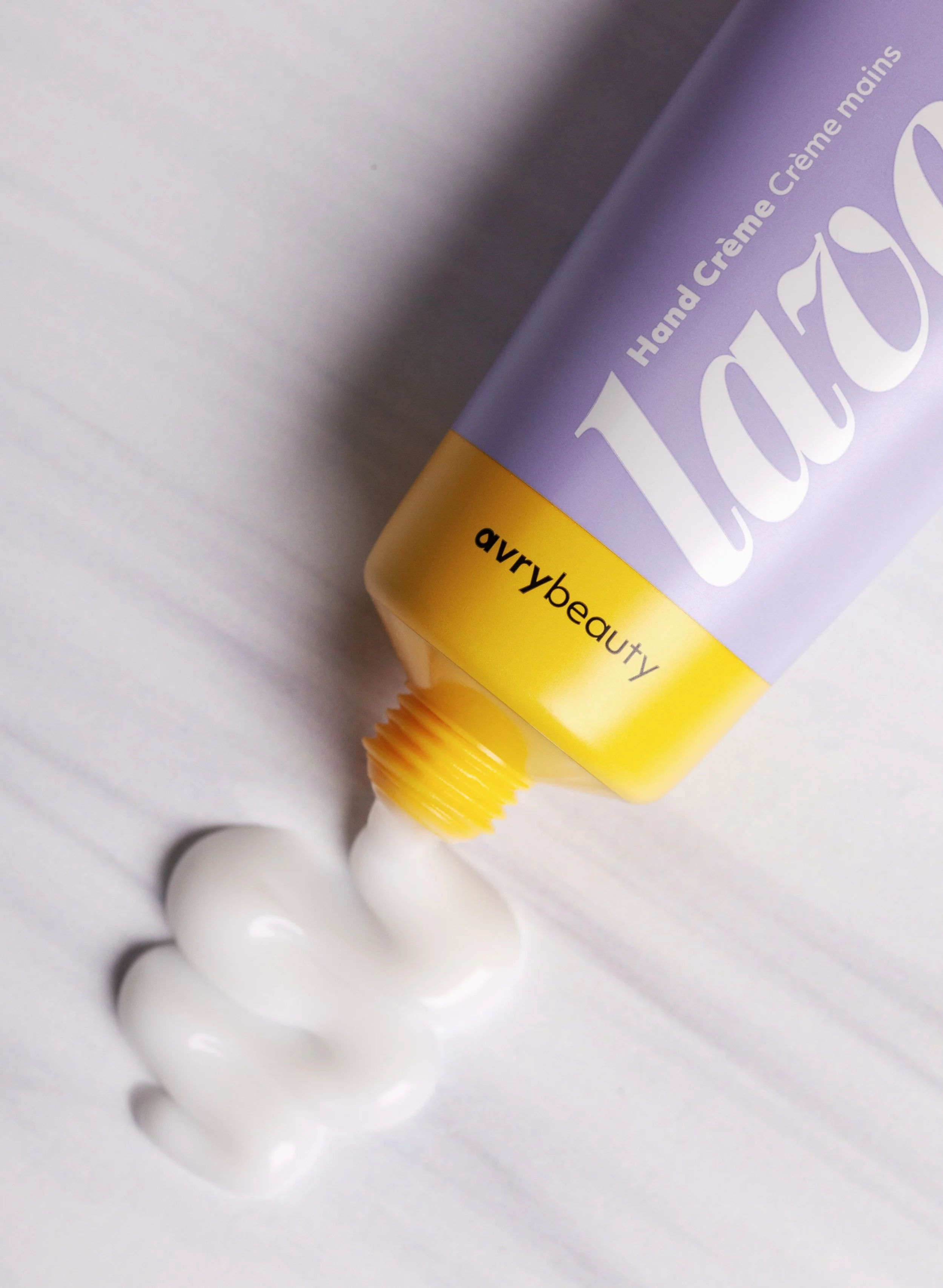 A tube of Avry lotion with a purple and yellow design, spilling out lotion.
