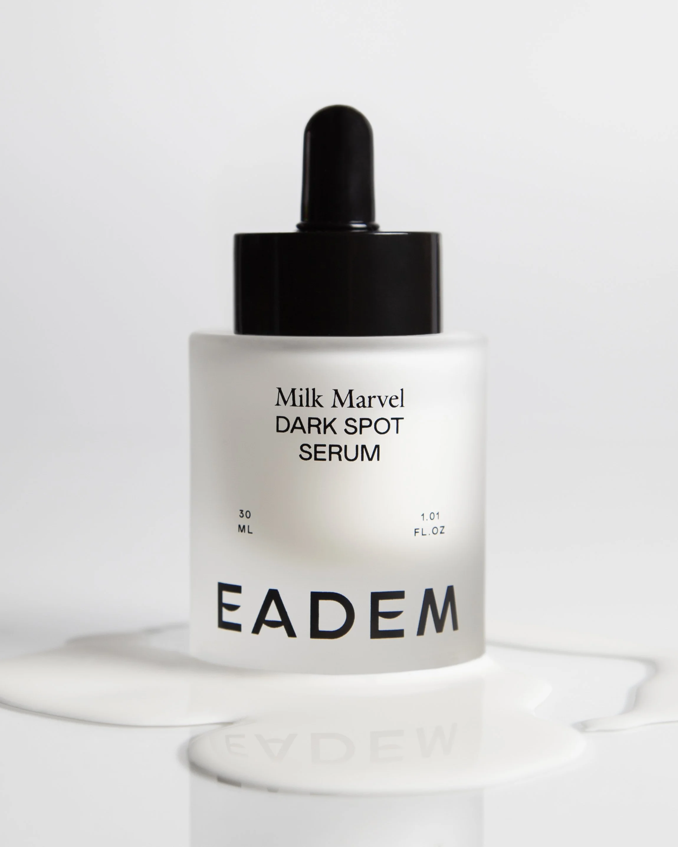 Close-up of a white bottle labeled 'Milk Marvel DARK SPOT SERUM' with a black dropper cap on a white background.