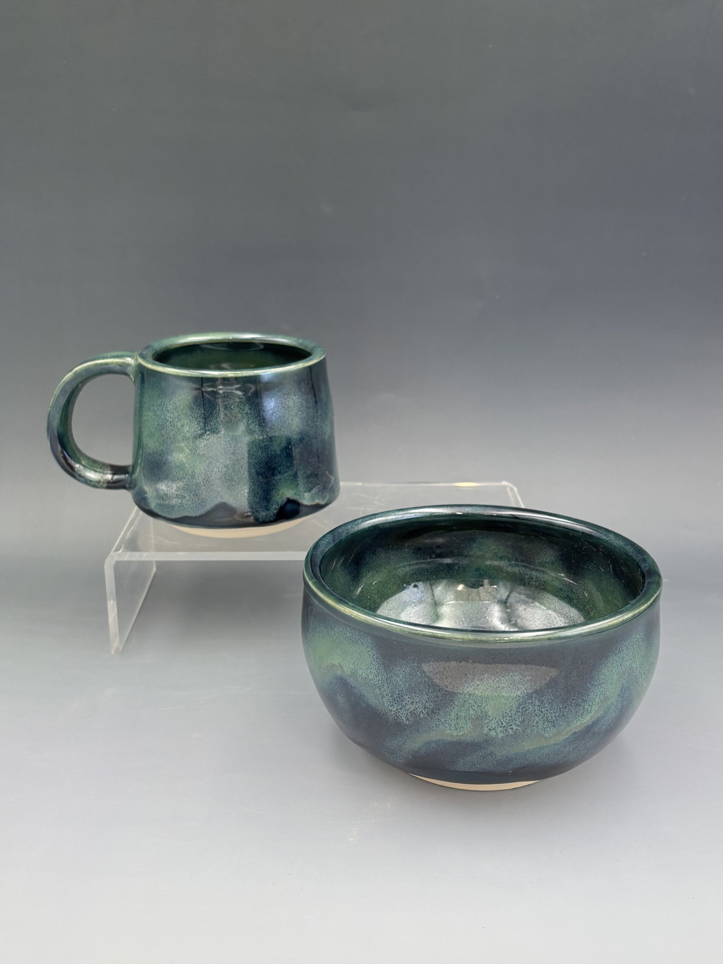 Handmade wheel-thrown ceramic mug and bowl by student Lisa Bowers in deep teal and midnight blue mottled glaze, made in Malenka Luckett's ceramics class