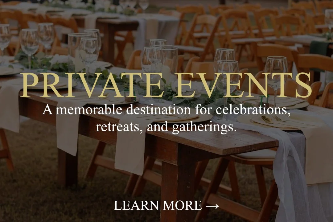 Elegant outdoor event setup with wooden tables, white tablecloths, glassware, and chairs, prepared for a private celebration or gathering.