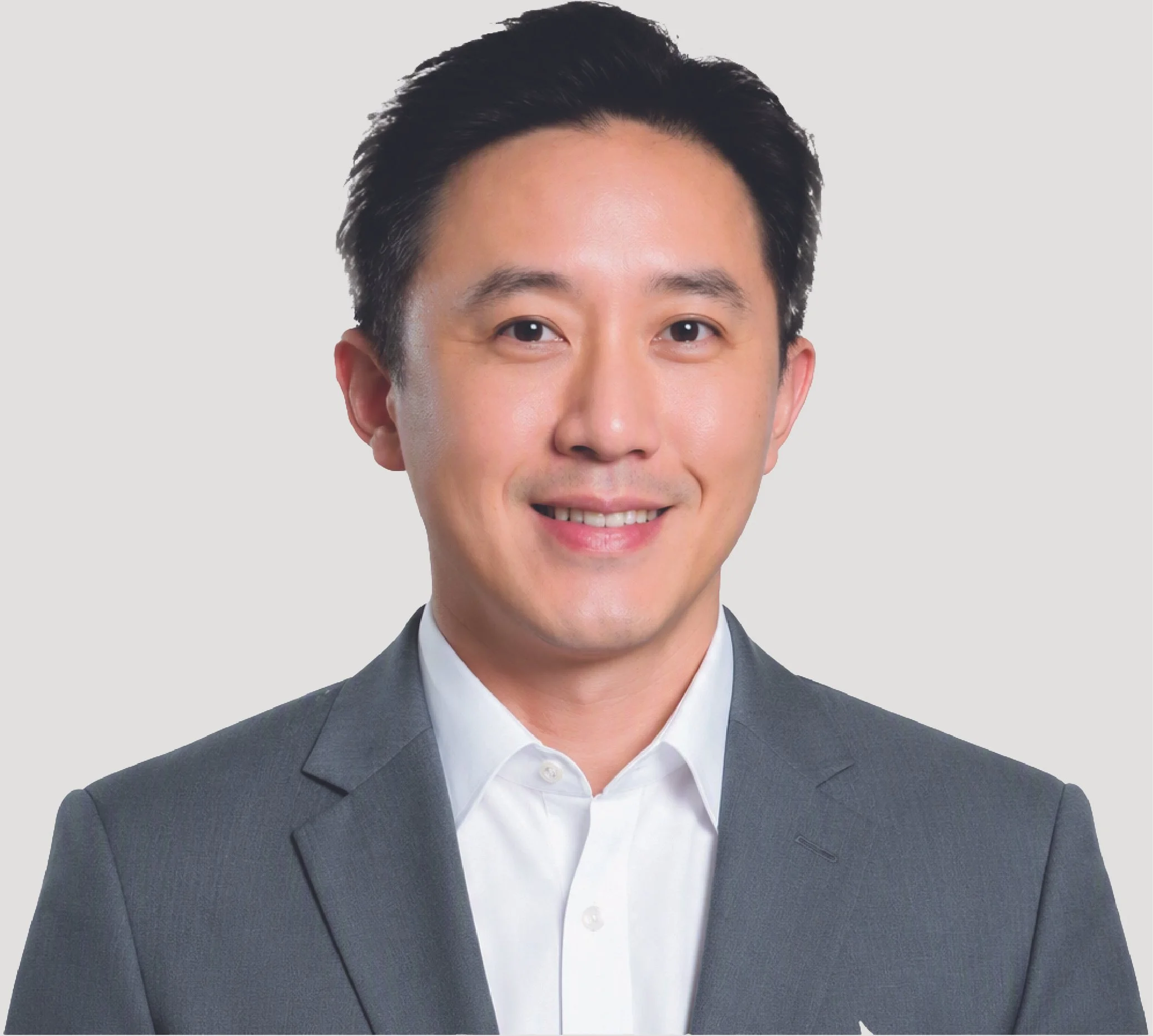 Close-up of a smiling Asian man with black hair, dressed in a gray business suit and white shirt, against a plain light gray background.