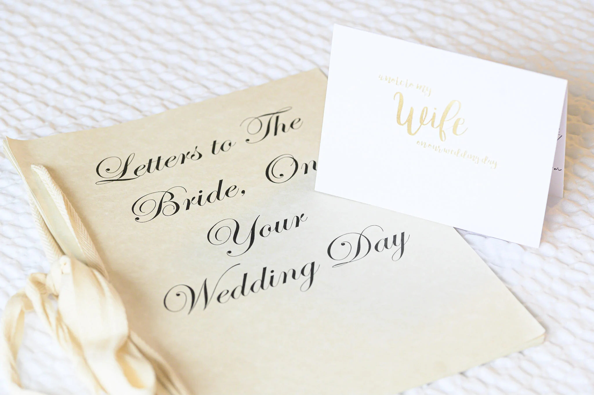 Close-up of wedding cards with elegant cursive writing on a textured white surface.