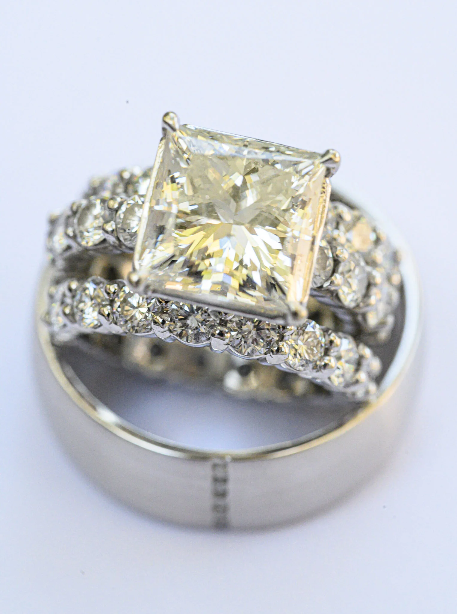 Close-up of a diamond ring with a large square-cut diamond surrounded by smaller diamonds.