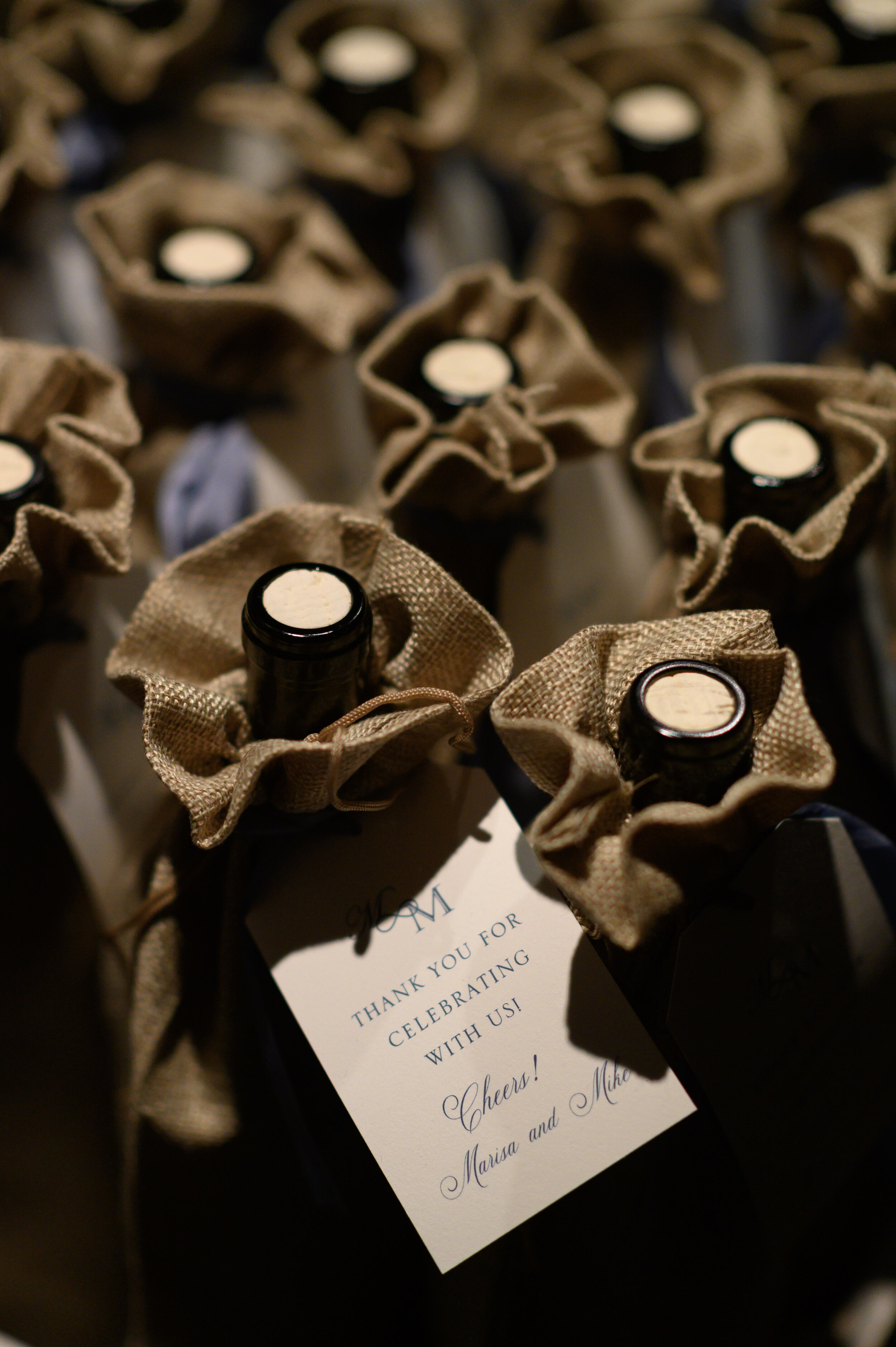 Multiple dark glass bottles with fabric-wrapped necks and small candles on top, arranged for celebration or gifting.