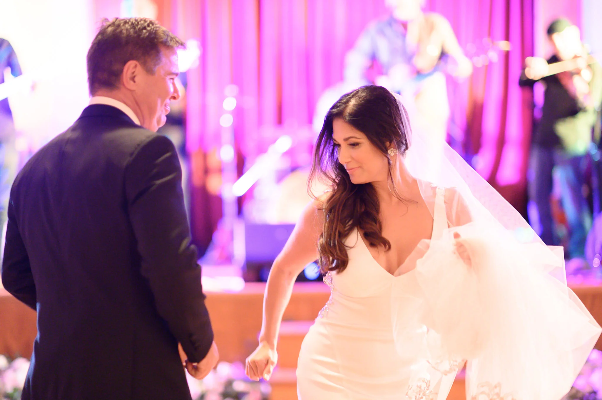 A bride and groom holding hands during their wedding ceremony with a band playing in the background.