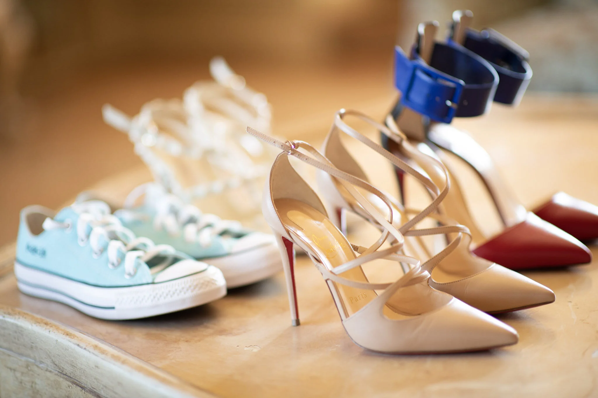 A display of various shoes including sneakers, high heels, and sandals on a wooden surface.