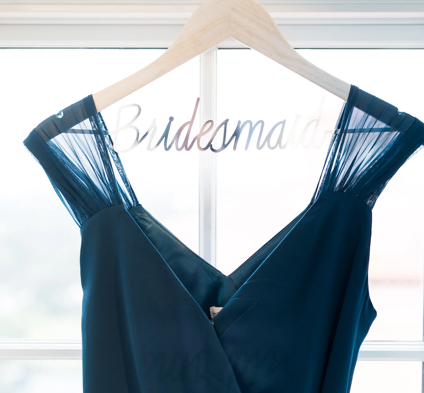 A pair of dark blue pajamas hanging on a wooden hanger with a sign that says 'Bridedm' in the background