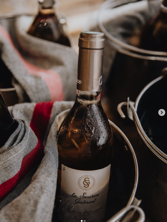 A bottle of red wine in an ice bucket surrounded by cloths and other bottles.