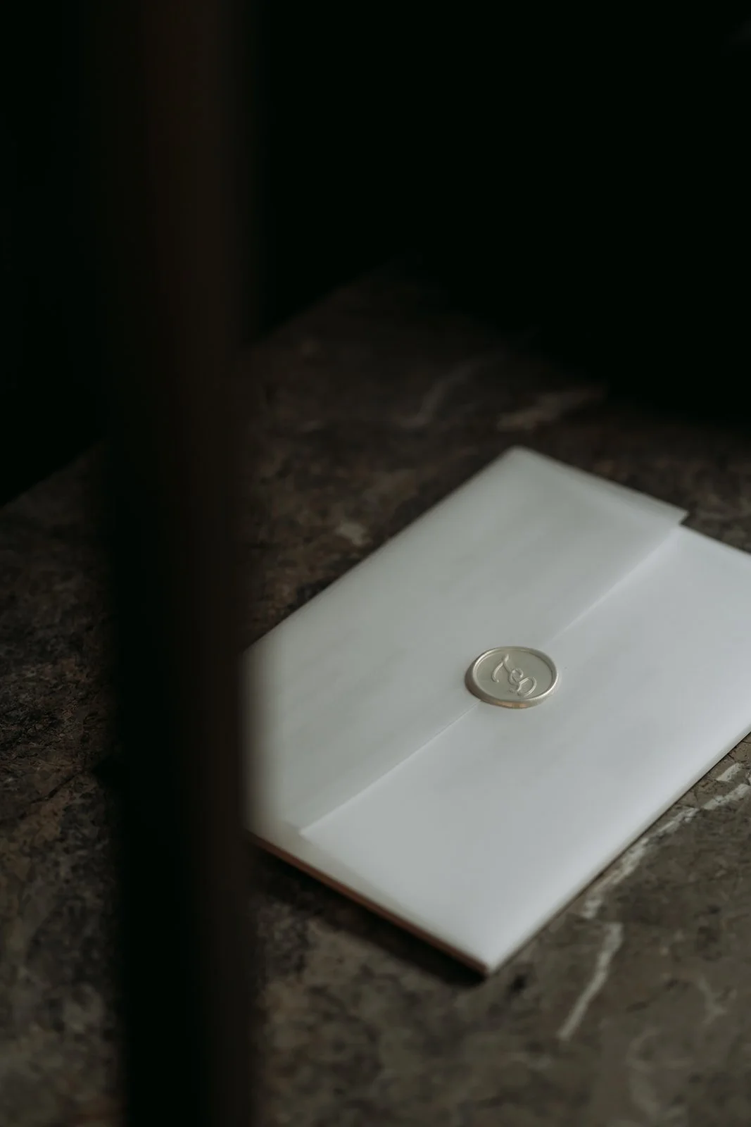 A silver coin placed on top of a white envelope, positioned on a dark, textured surface.