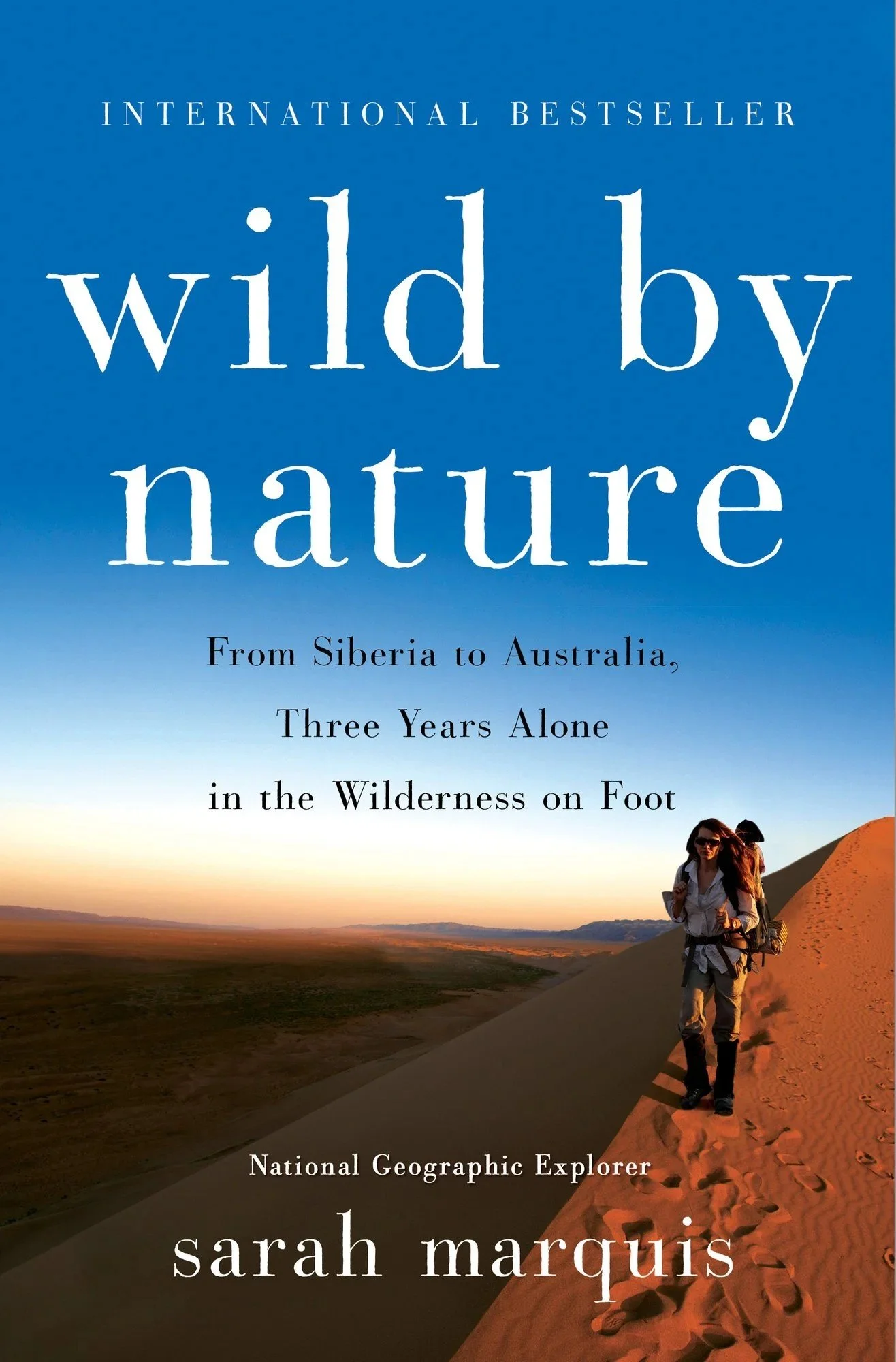 Book cover for "Wild By Nature" by Sarah Marquis, showing a woman hiking in a desert landscape at sunset.