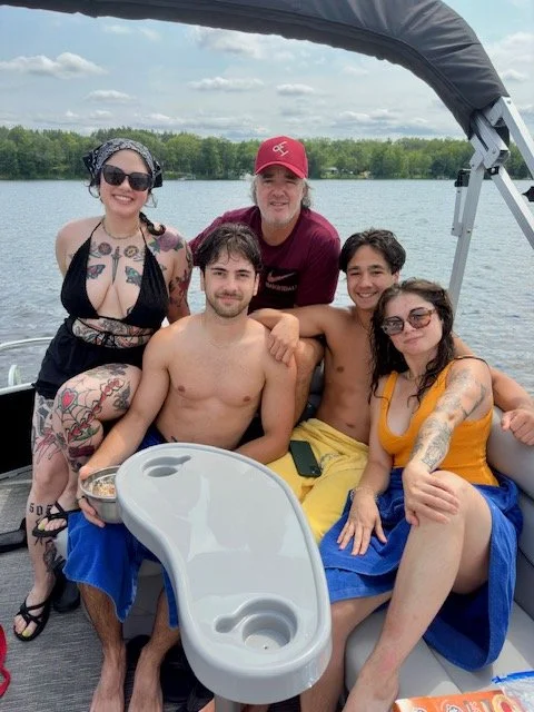 Group of five people enjoying a boat ride on a lake in Wisconsin with trees in the background, smiling and relaxing.