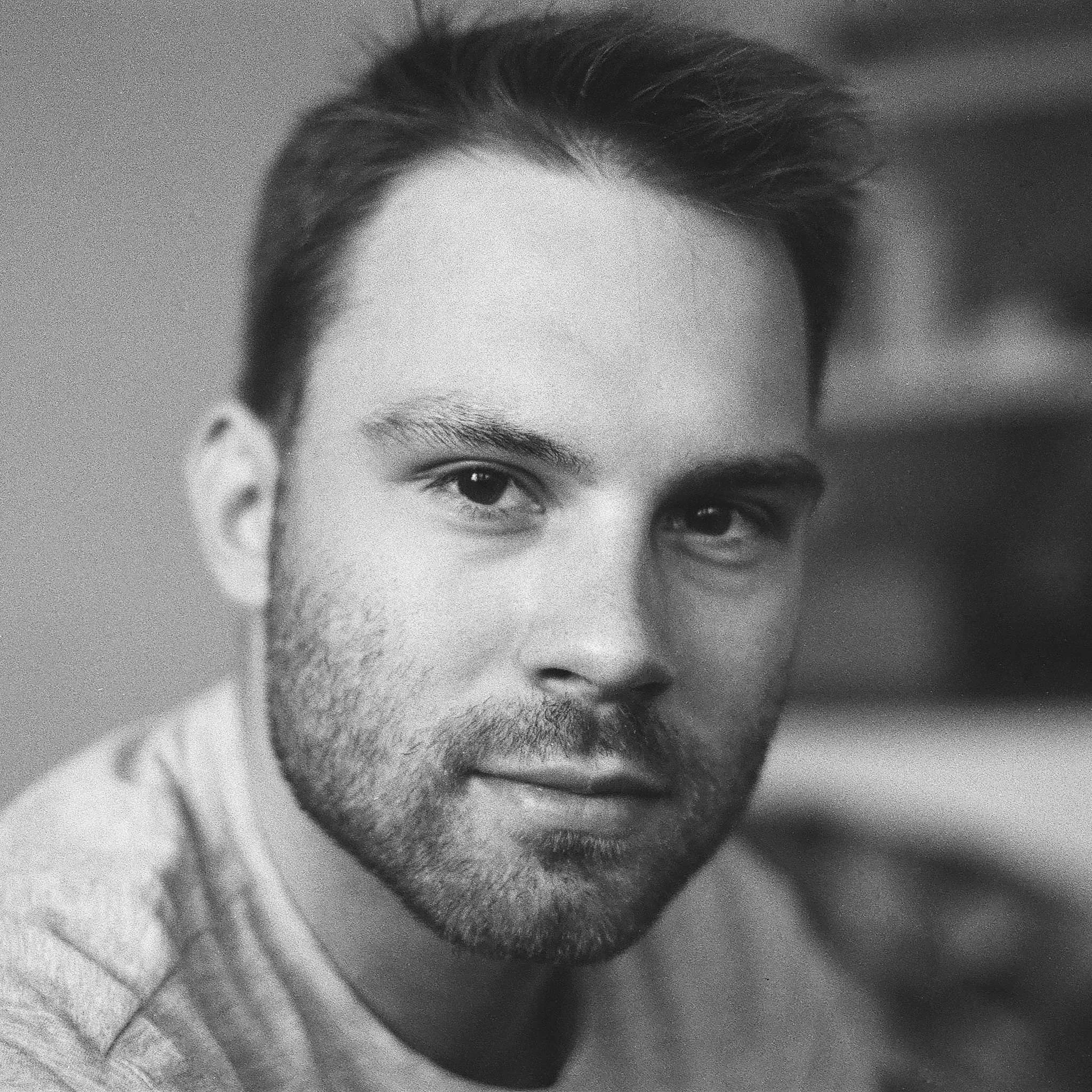 Close-up of a person's face, showing one eye and eyebrow, with hair and facial hair visible.
