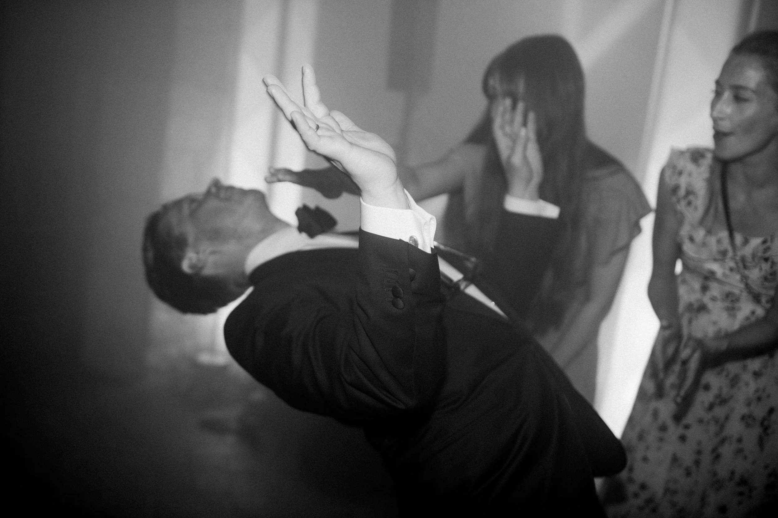 Immagine in bianco e nero di due persone sedute con i loro telefoni alle orecchie, una di fronte all'altra, con una mano in primo piano che fa il gesto di 'no'.