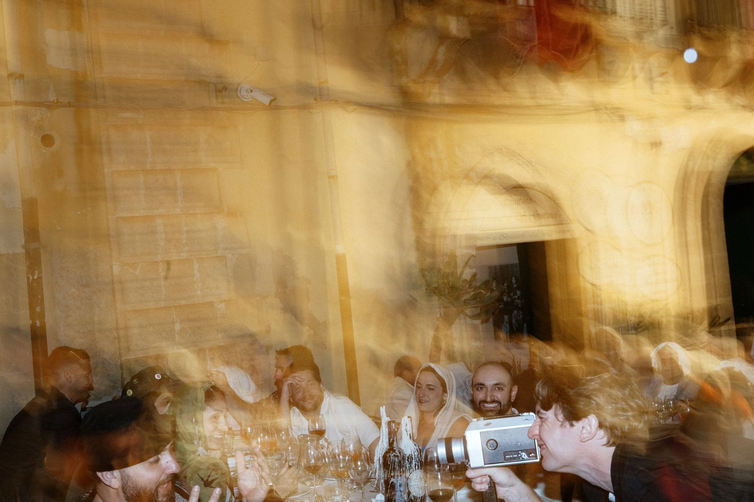Un gruppo di persone sedute a un tavolo durante una cena, sorridenti e che si divertono, con un ambiente caldo e accogliente.