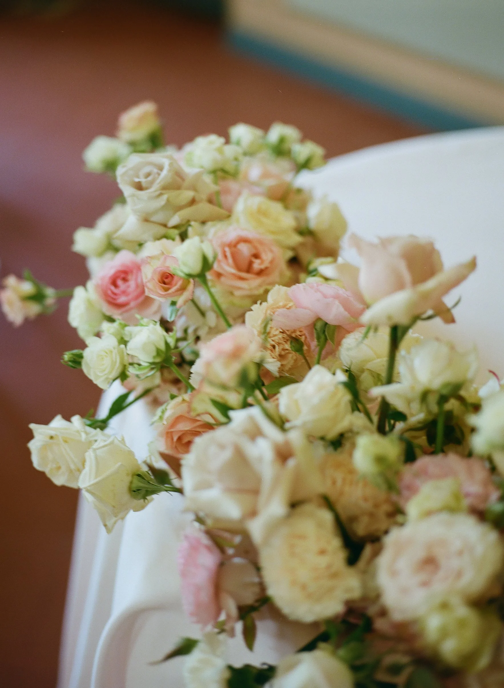Coroncina di fiori di vari colori, prevalentemente bianchi, rosa e gialli su fondo sfocato