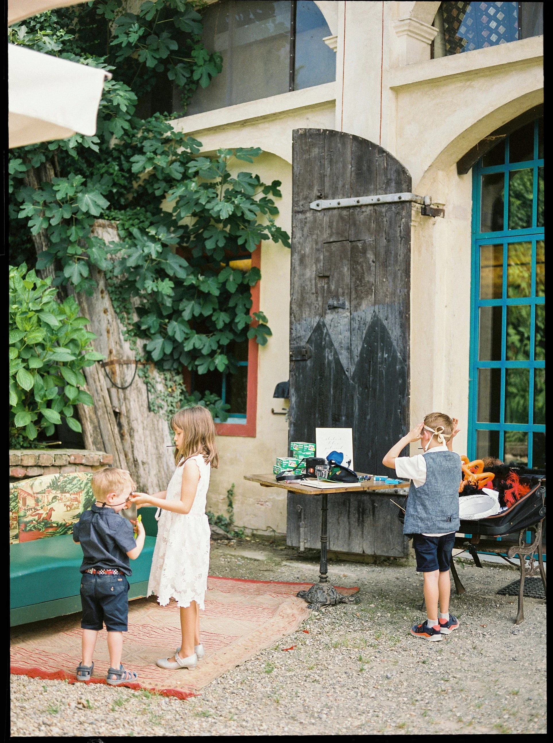 Bambini che giocano e socializzano in un cortile all'aperto, con alcuni strumenti e oggetti sul tavolo.