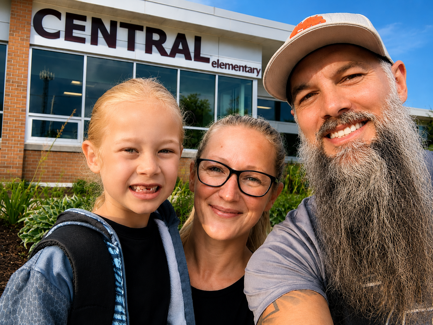 Family taking a selfie in front of Central Elementary School, with a girl, woman, and man smiling.