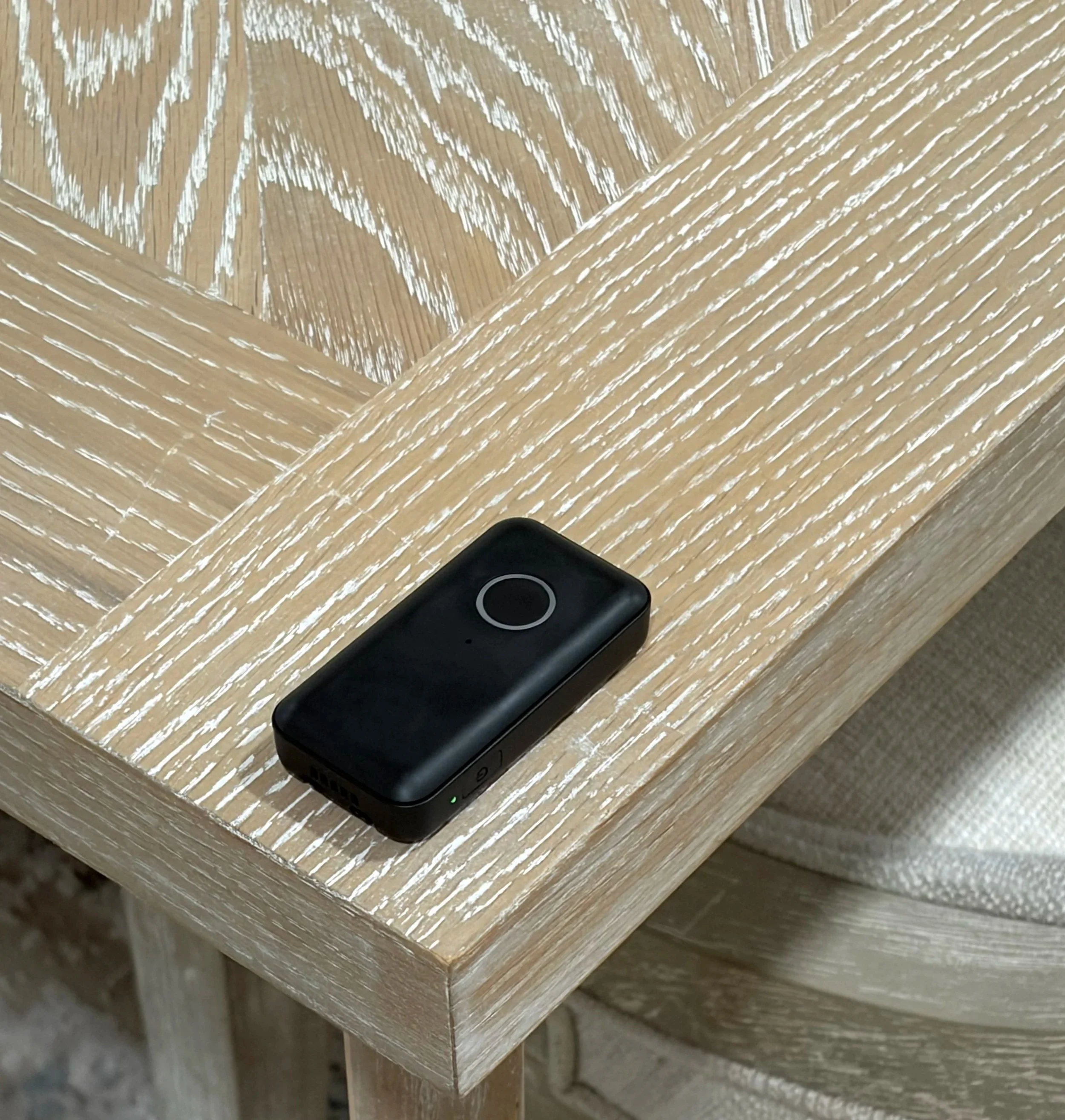 A portable health monitoring device resting on the edge of the table to show how small it is.