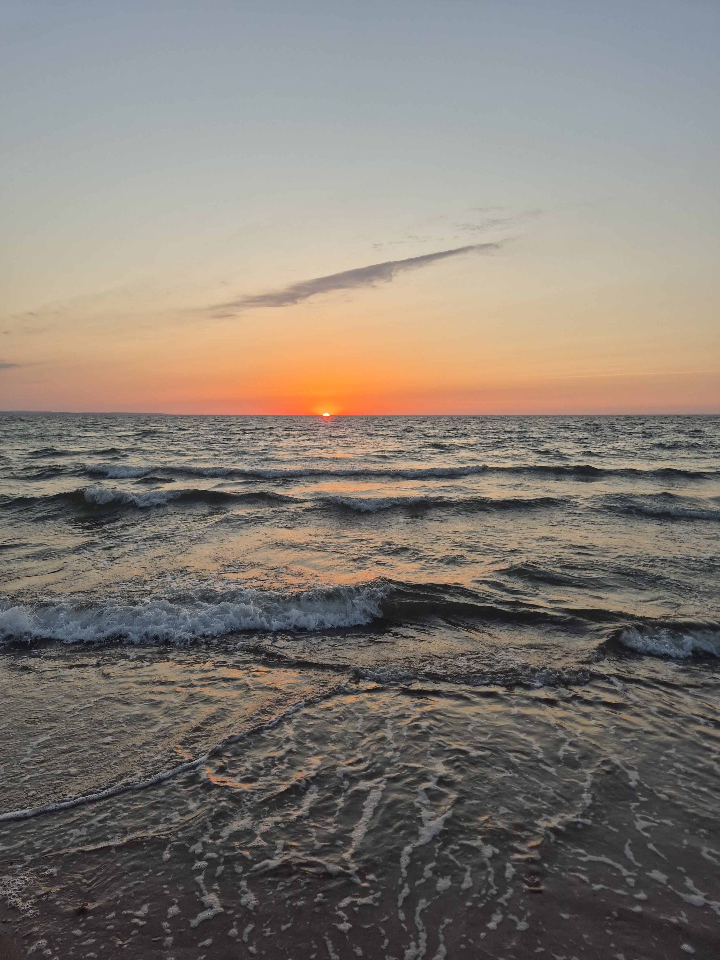 Sonnenuntergang über dem Meer mit Wellen am Strand Ostholstein. 