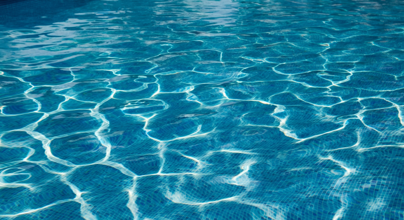 The image shows the surface of a swimming pool with clear blue water and ripples.