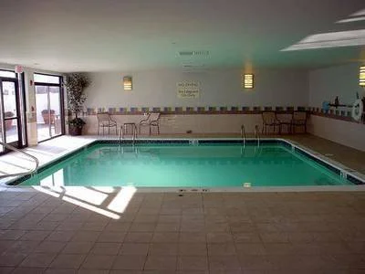 Indoor swimming pool with chairs along the wall and a glass door to the outside.