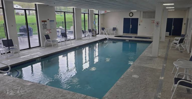 Indoor swimming pool area with chairs along large windows and an outdoor view
