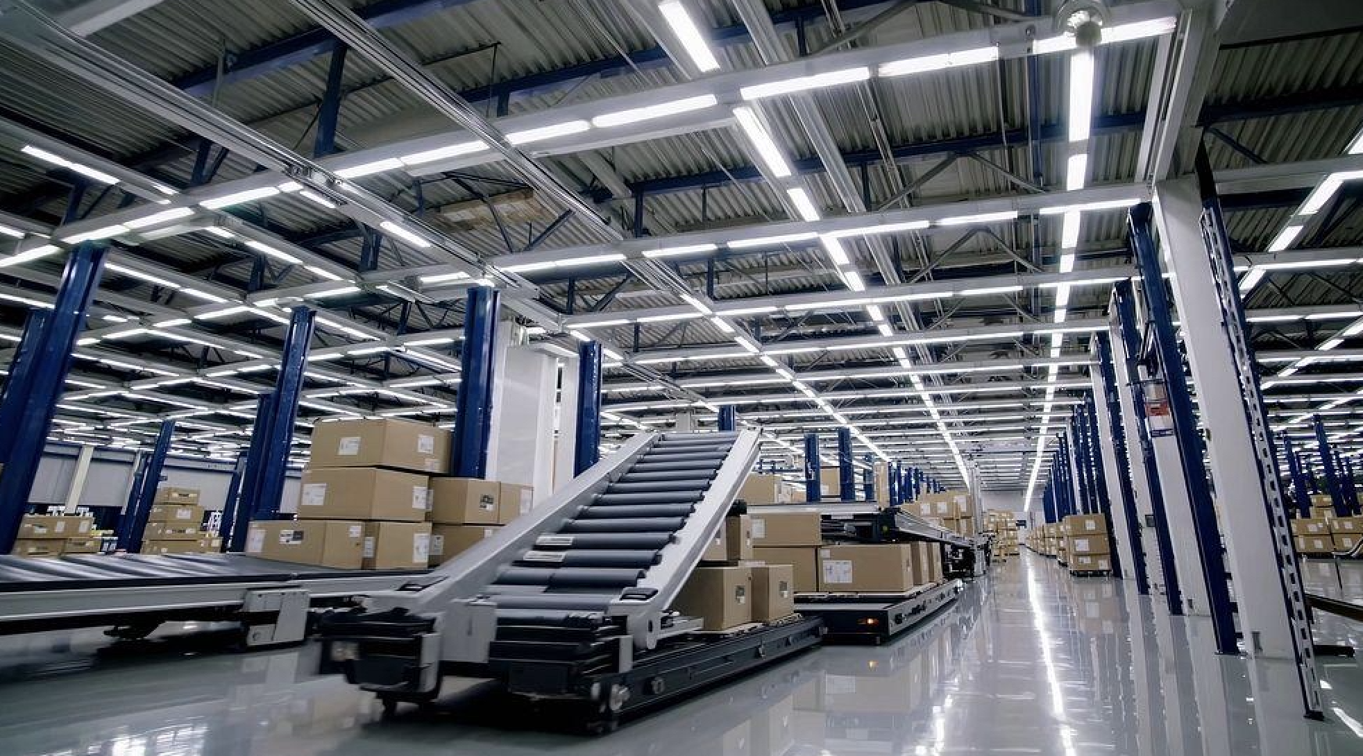 Interior of a warehouse with storage racks and boxes, with a conveyor belt and slide.