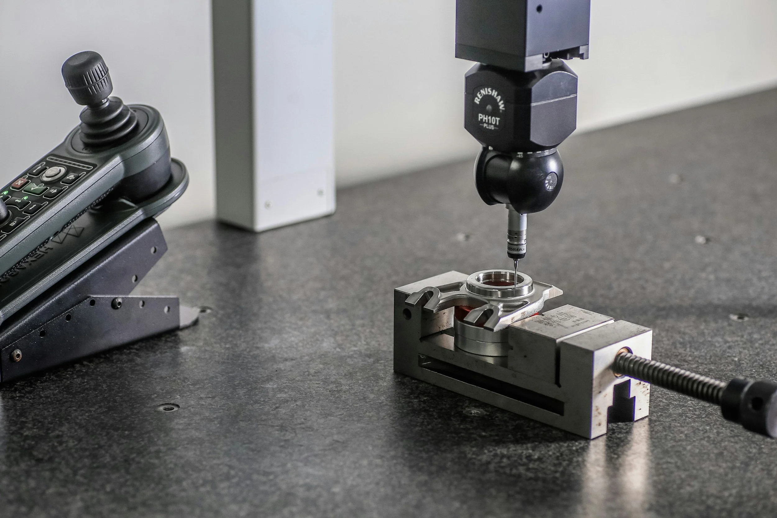 CMM touch probe measuring a machined part on a granite inspection table