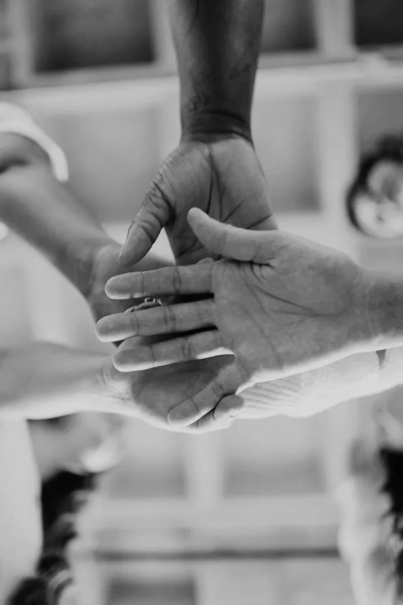 Close-up of two hands intertwined, one hand is darker-skinned and the other is lighter-skinned.