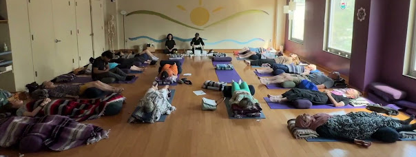 Participants lying on yoga mats during a group acupuncture and sound healing session in a studio