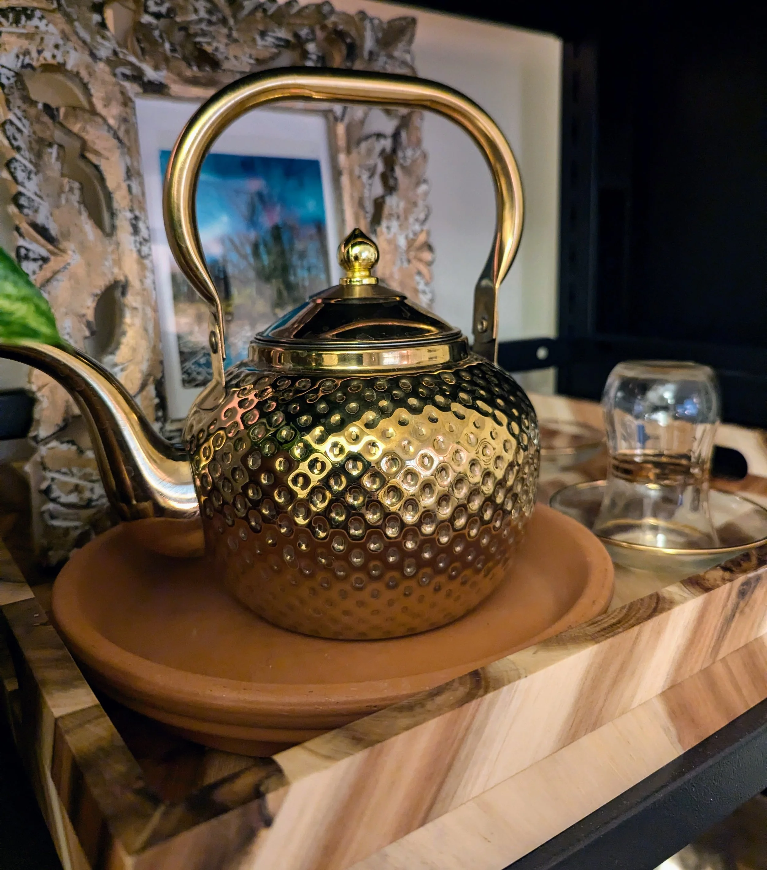 A gold teapot on a wooden tea tray
