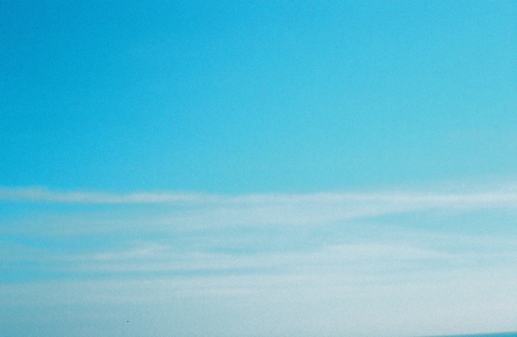 Clear blue sky with some white clouds or contrails at the bottom.