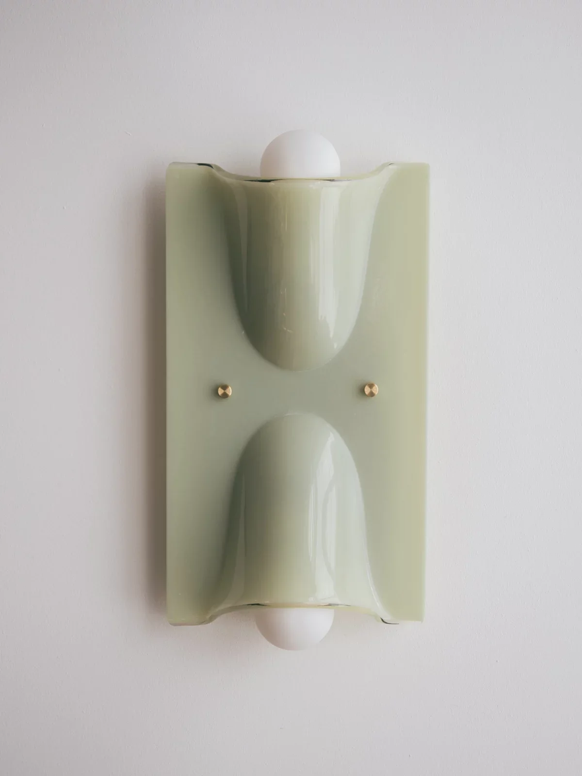 Modern wall-mounted soap dish with a white spherical soap on top, mounted on a white wall.