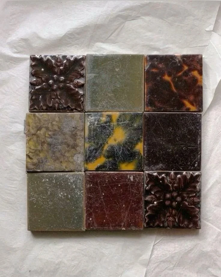 Nine decorative soap bars arranged in a 3x3 grid on white paper, with some featuring floral or marbled designs.