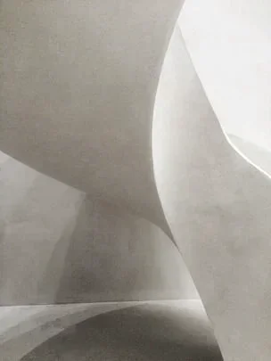 Close-up of a modern, curved, white architectural structure with smooth surfaces.