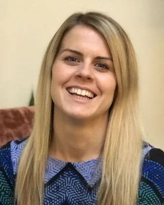 Close-up of smiling woman with long blonde hair and blue patterned top