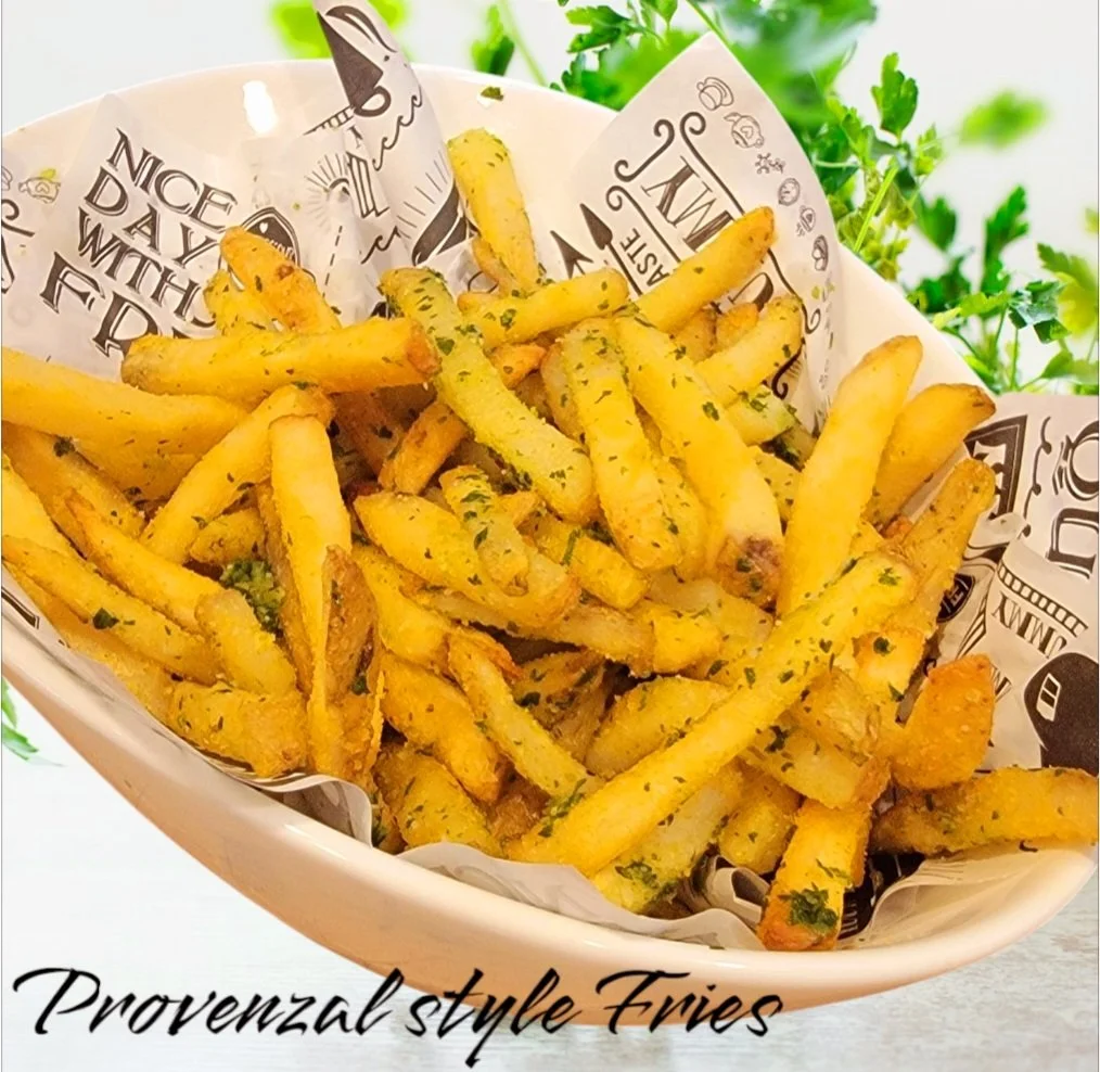 Provenzal style fries in a basket lined with decorative paper, garnished with herbs.