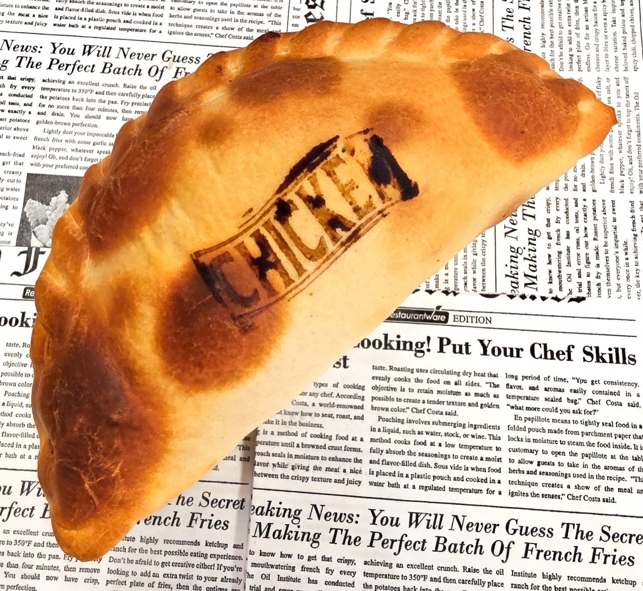 A baked pastry with the word 'KETCHUP' stamped on its surface, resting on a background of black and white newspaper print.