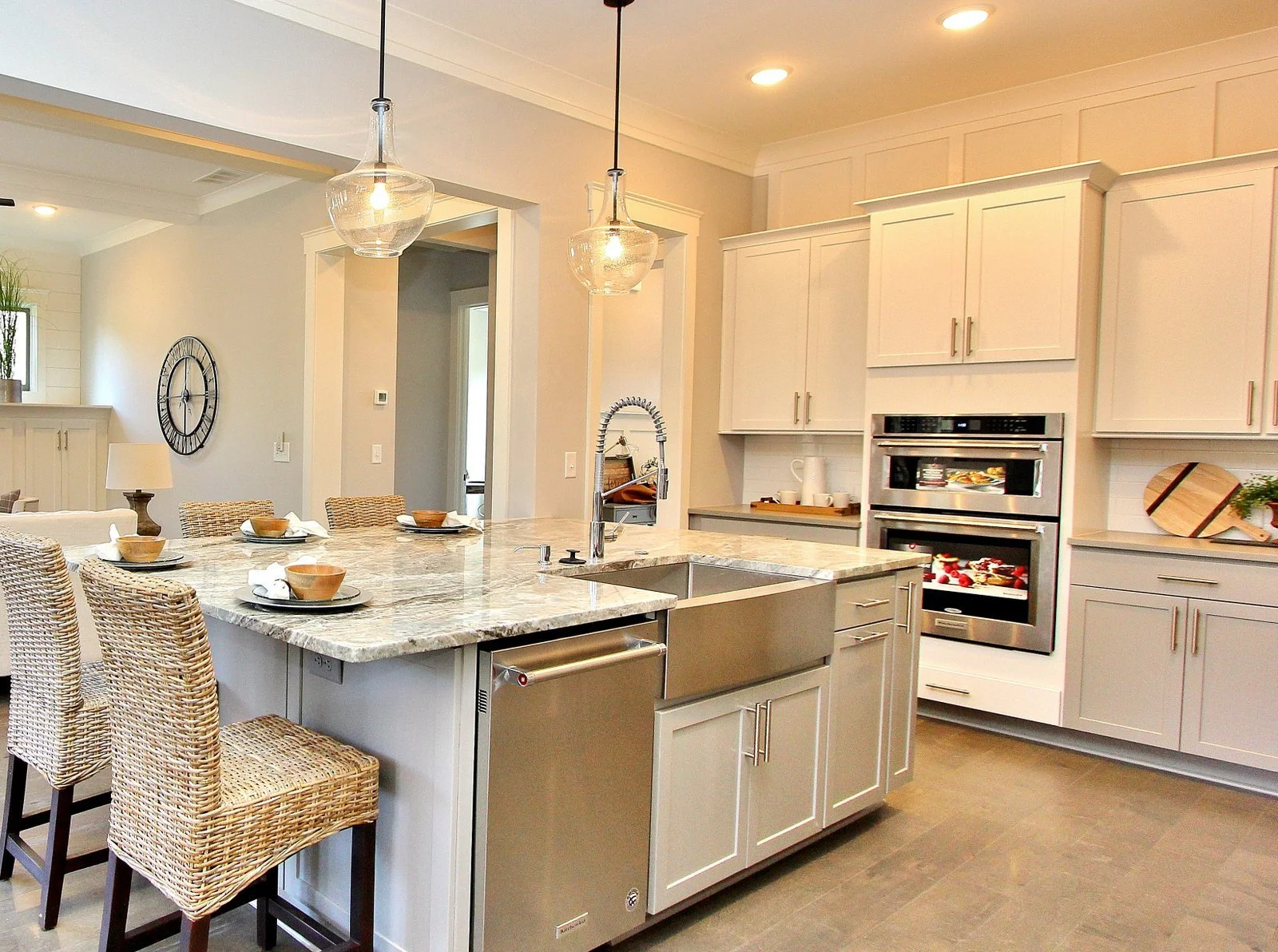 Modern kitchen with island counter, built-in oven, white cabinets, and hanging pendant lights.