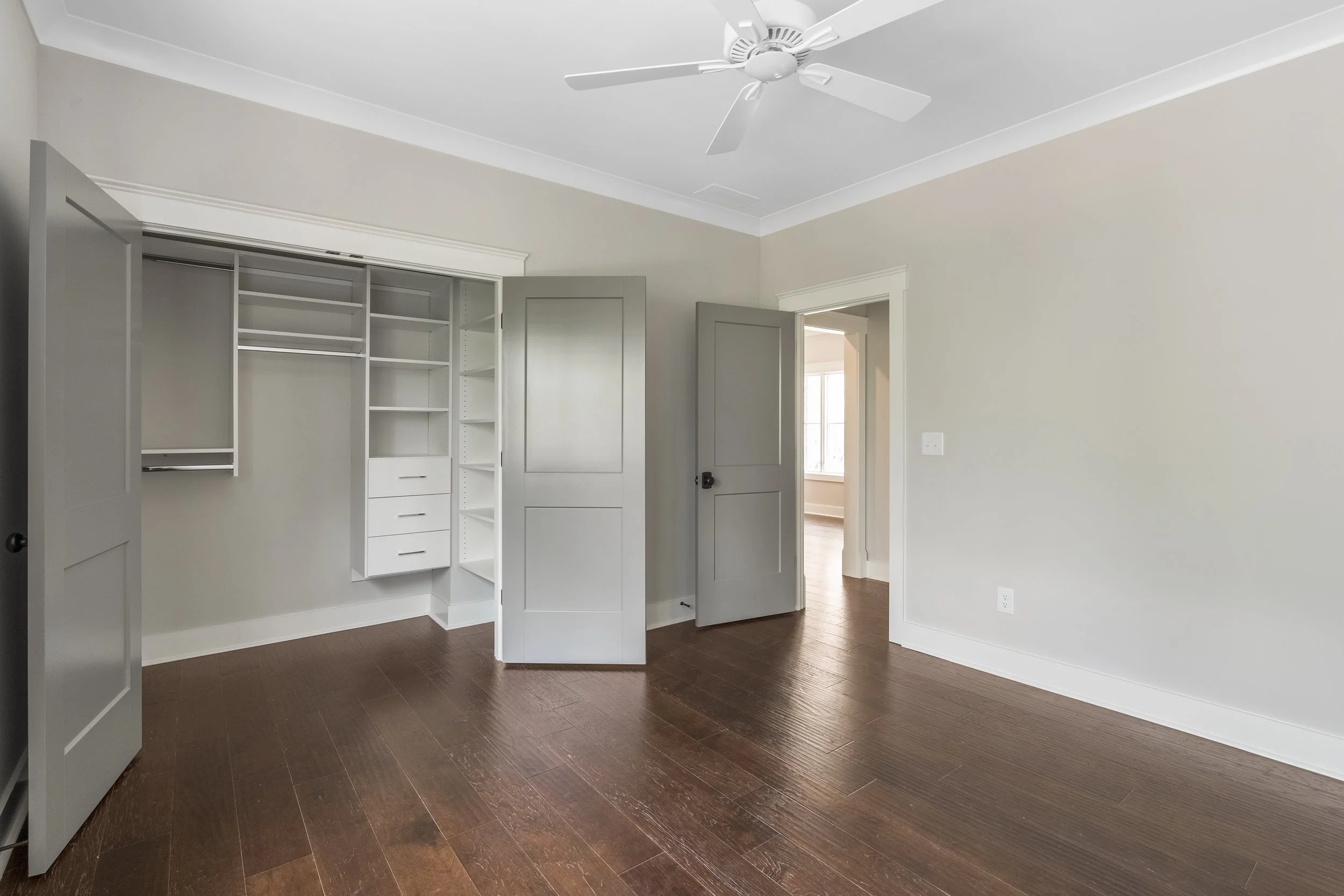 Empty room with a ceiling fan, an open closet without doors, and hardwood floors.