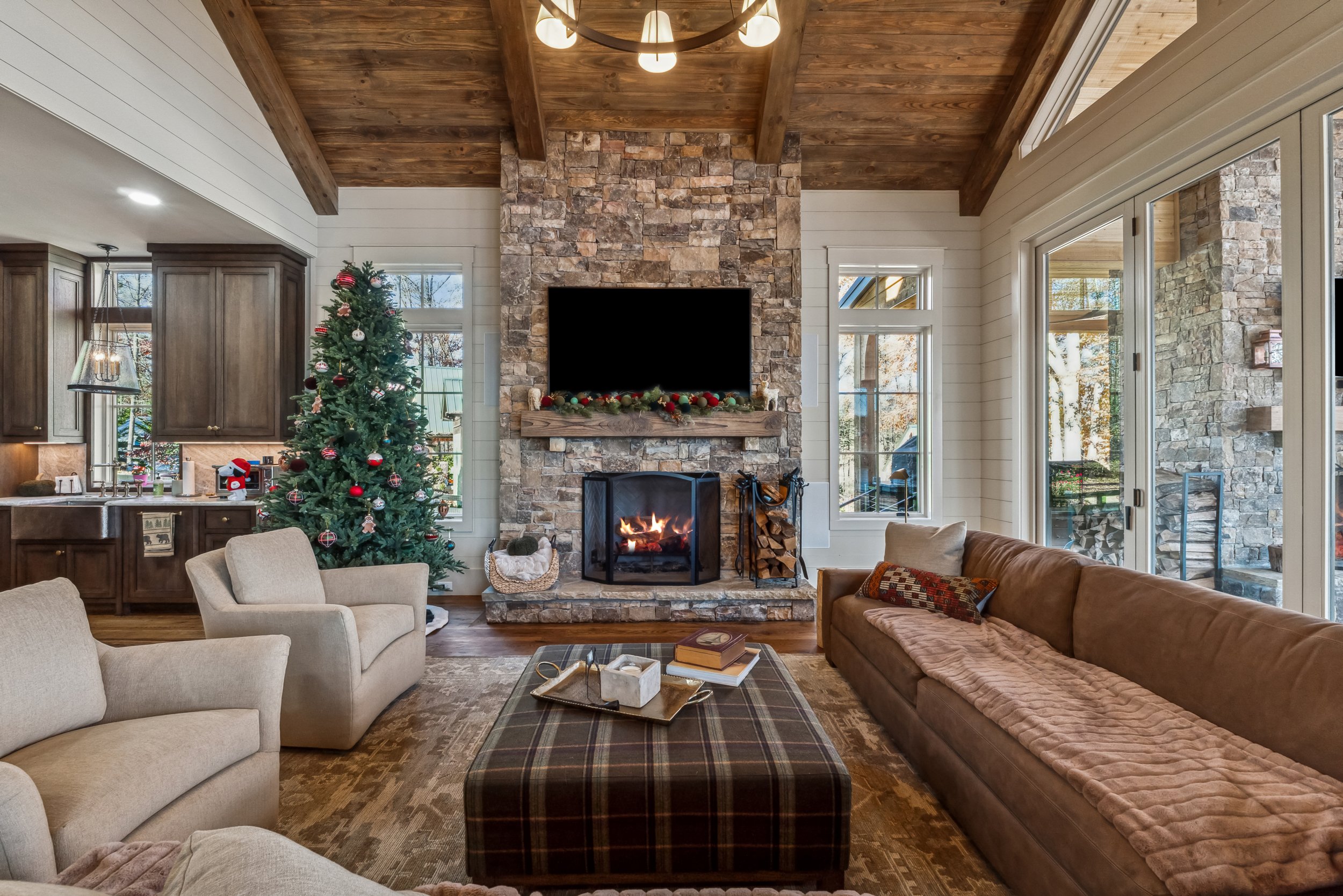 Living room with a Christmas tree, a fireplace, multiple windows, and a sofa.