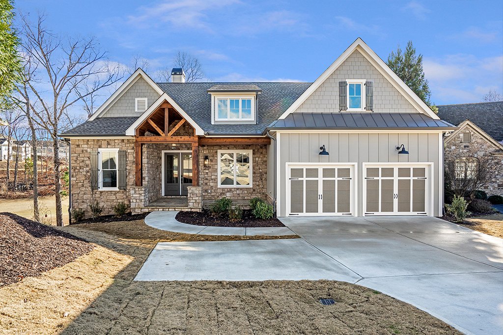 Front view of a modern two-story house with stone and siding exterior, two-car garage, and a landscaped yard.