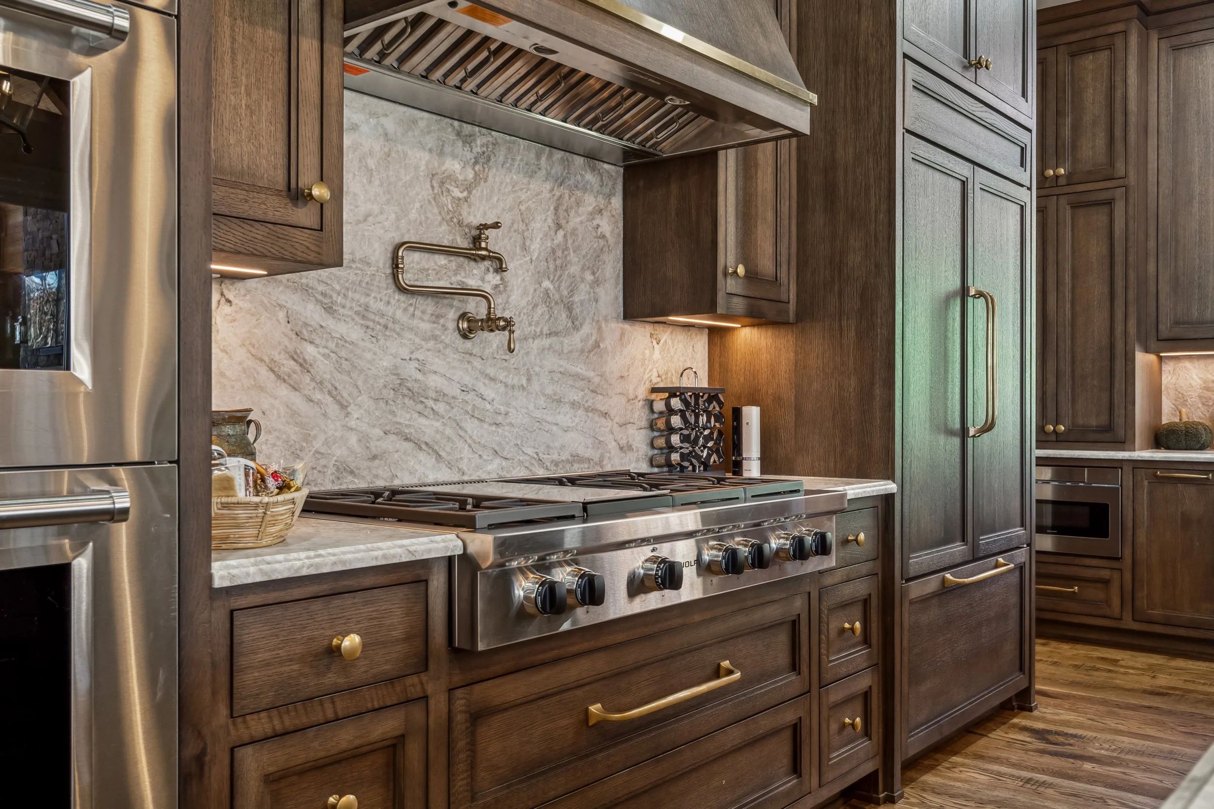 A kitchen with dark wood cabinets, a marble countertop, stainless steel appliances, and a gas stove.