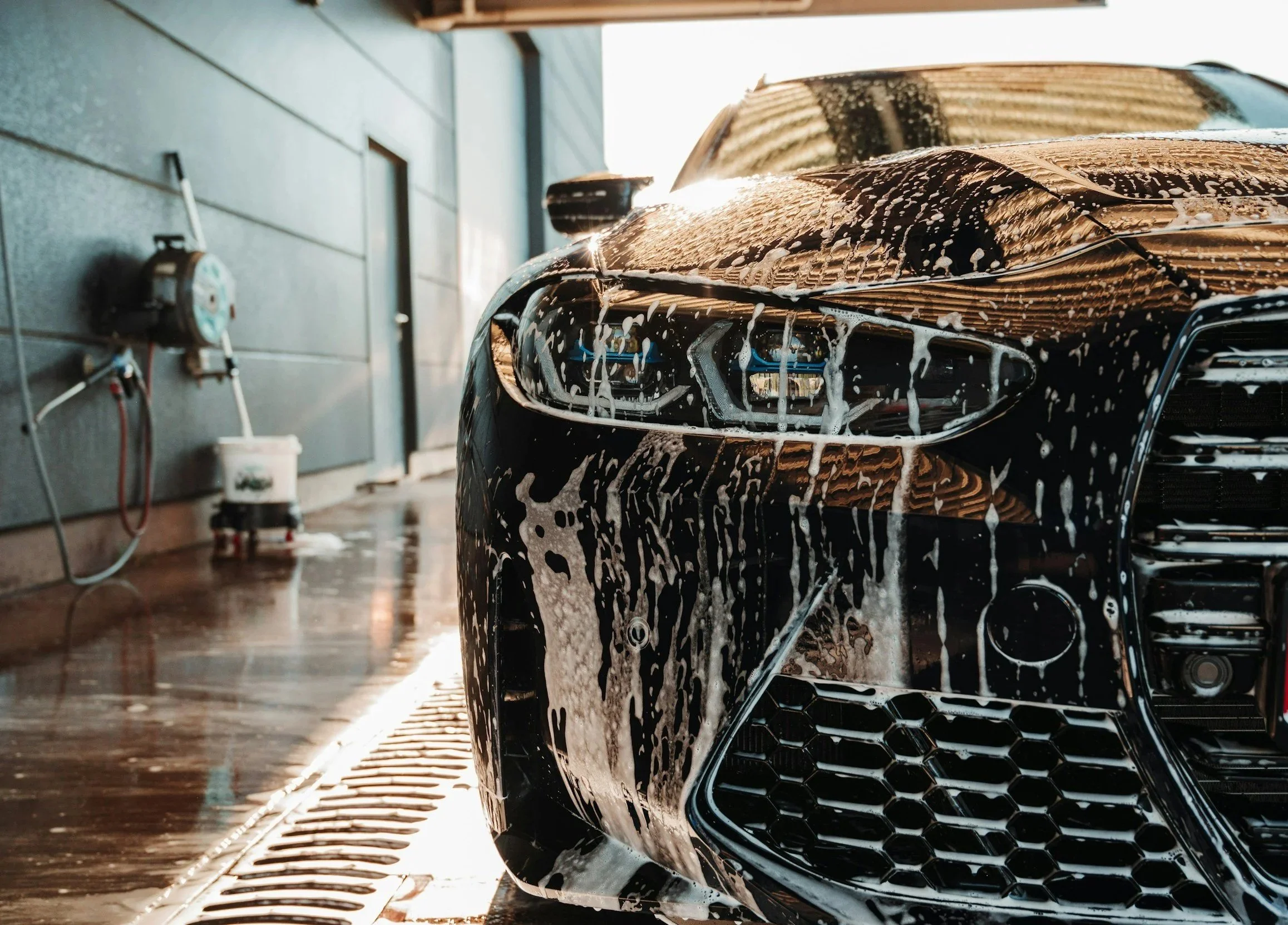 Professional mobile car detailing service washing a luxury vehicle with thick foam in Ocala, FL