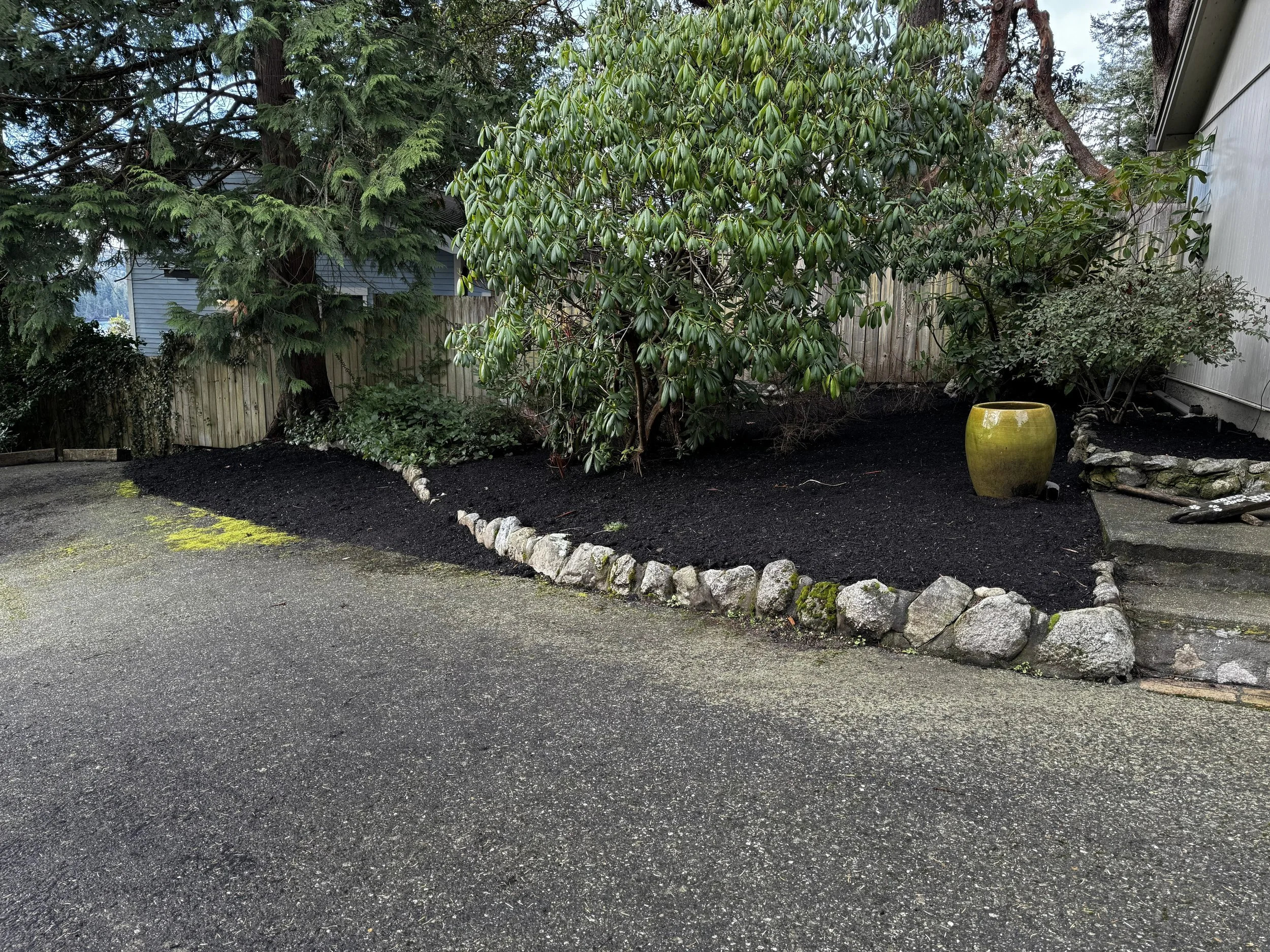 A two-car garage at the street entrance has mature rhododendrons in the gardens right outside the man door. There is room for a shop at the south end of the garage. 