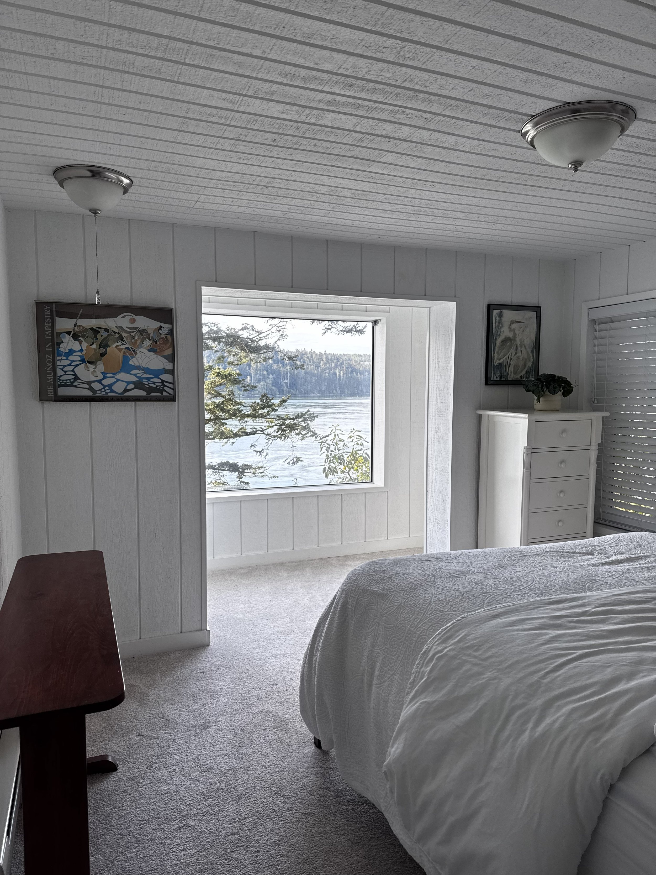 Downstairs offers a quaint guest bedroom with a sitting area and paneled walls. There is a laundry in a closet right outside the guest bedroom.  There is a guest bathroom with a shower. 