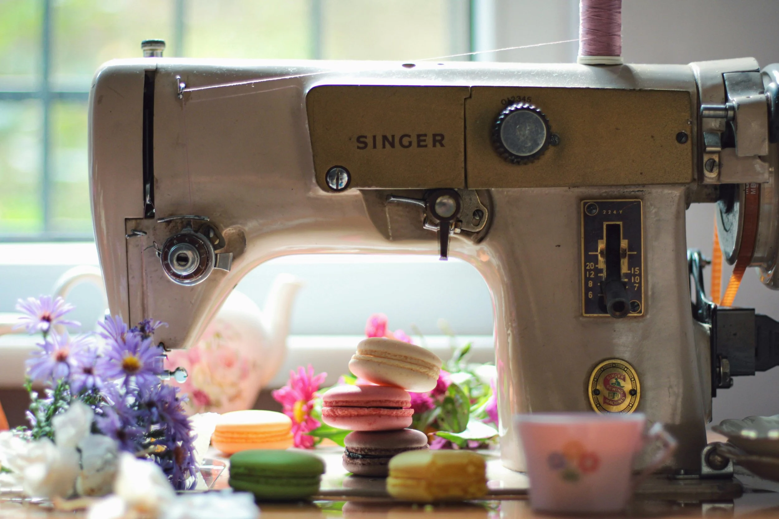Sewing machine by window with macaroons