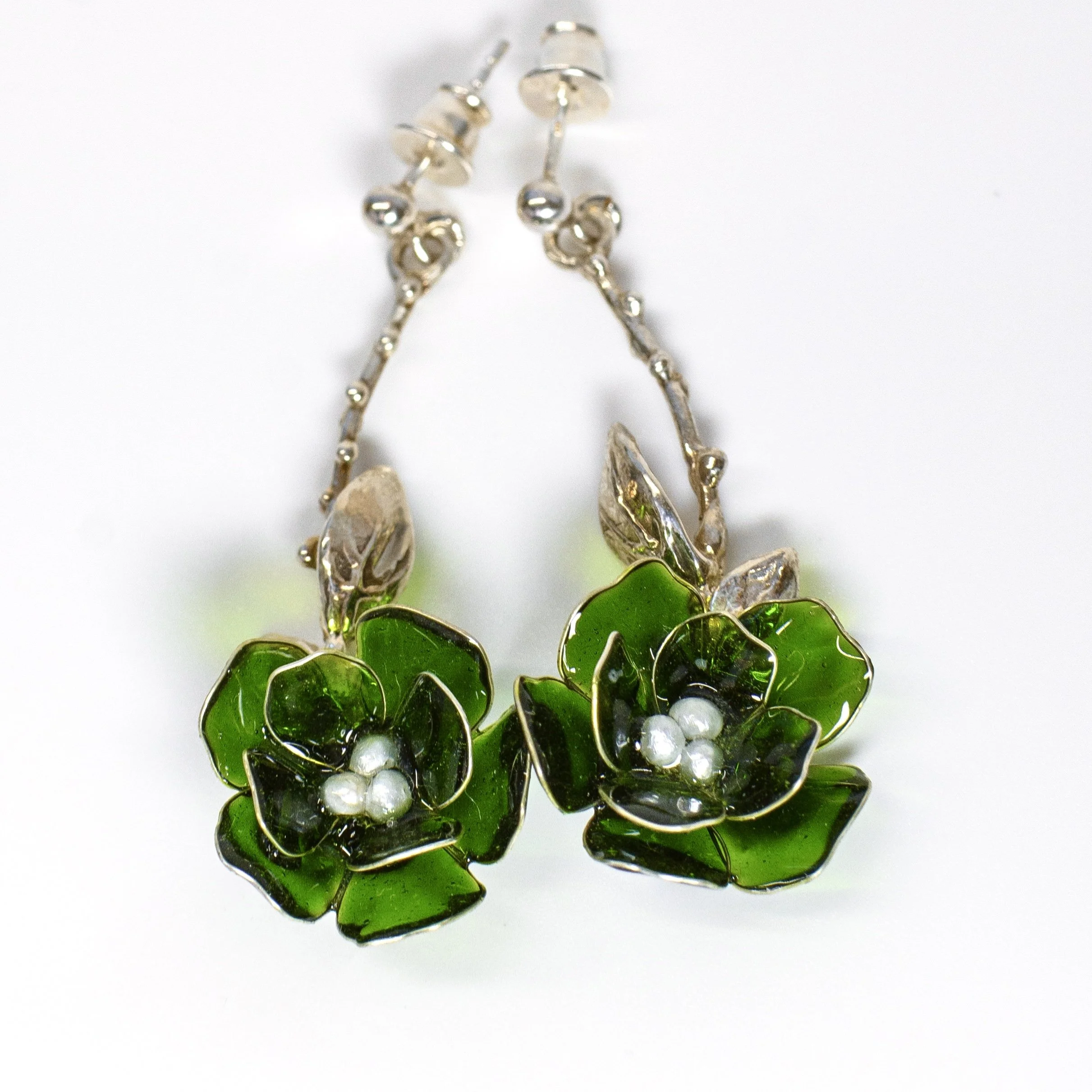 Close-up of green and silver earrings with leaf-shaped design, set against a white background.