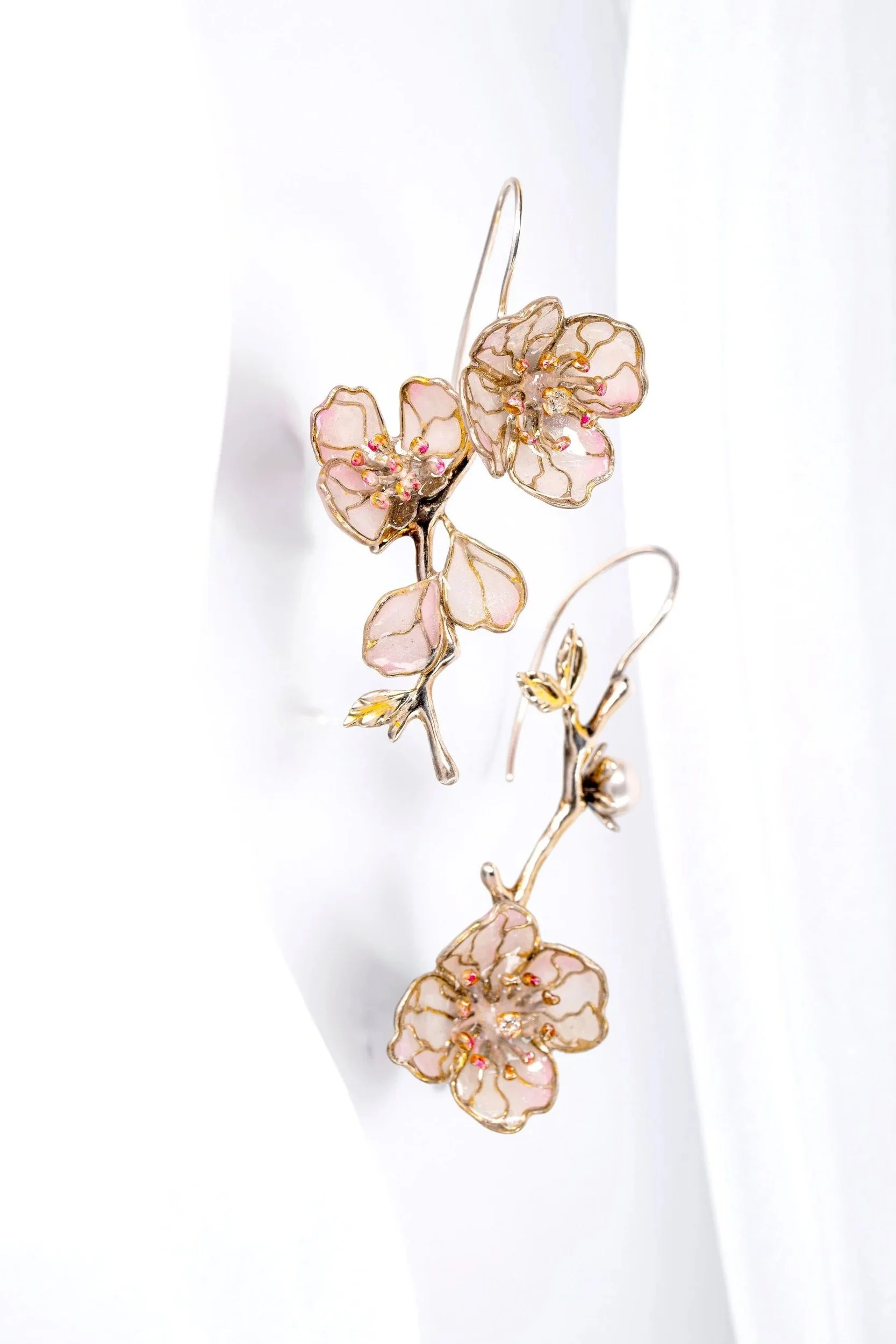 Close-up of a decorative jewelry piece featuring pink and gold floral design with small pink and clear gemstones.